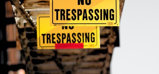 A yellow no trespassing sign hanging from construction beams